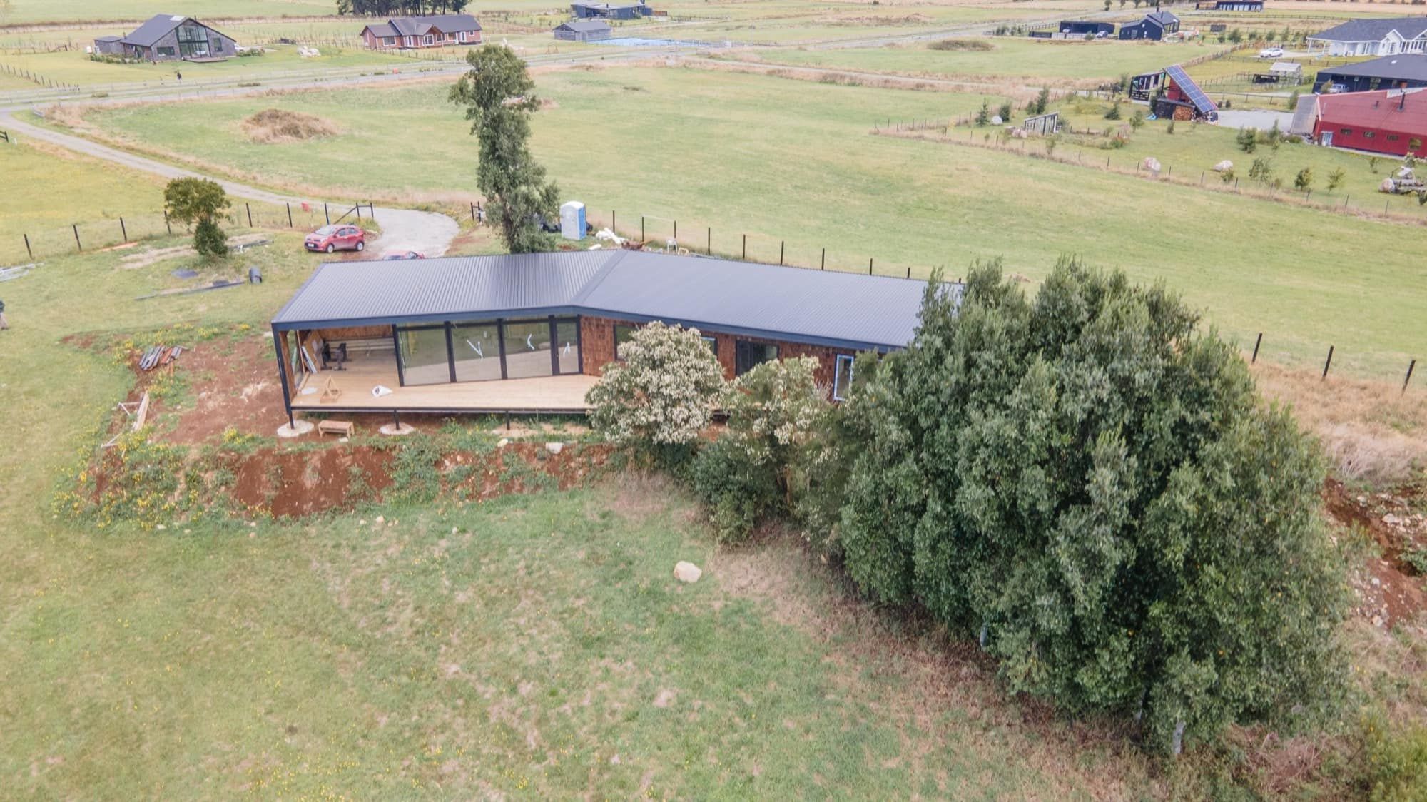 Vista aérea de la casa sobre la loma, junto al árbol