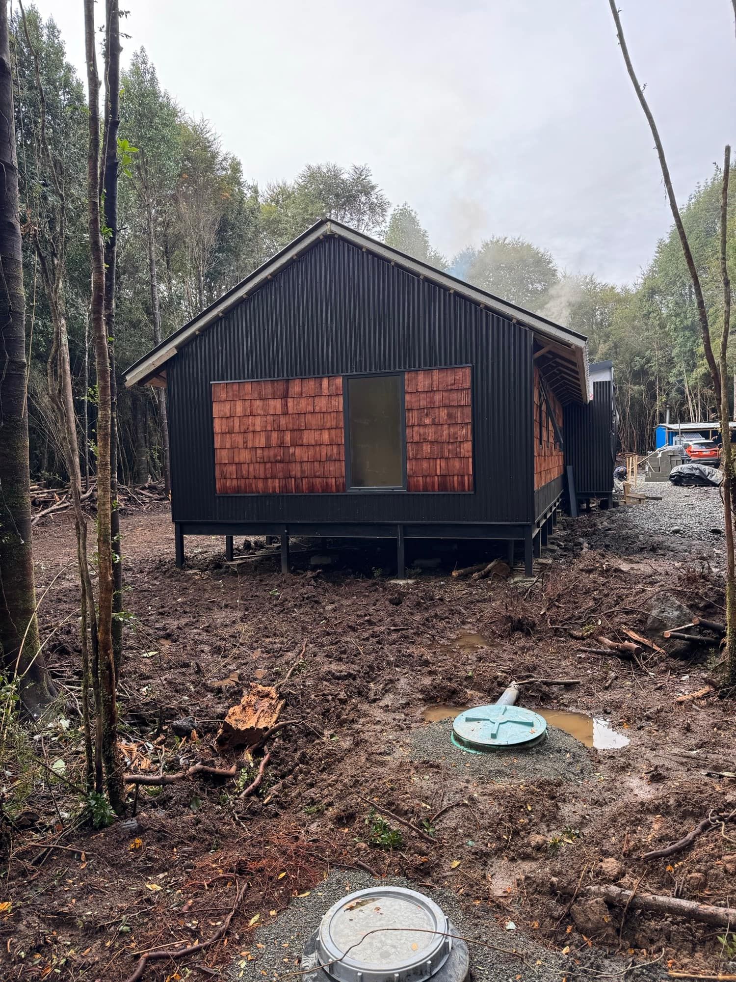 Vivienda negra en avance, rodeada de árboles