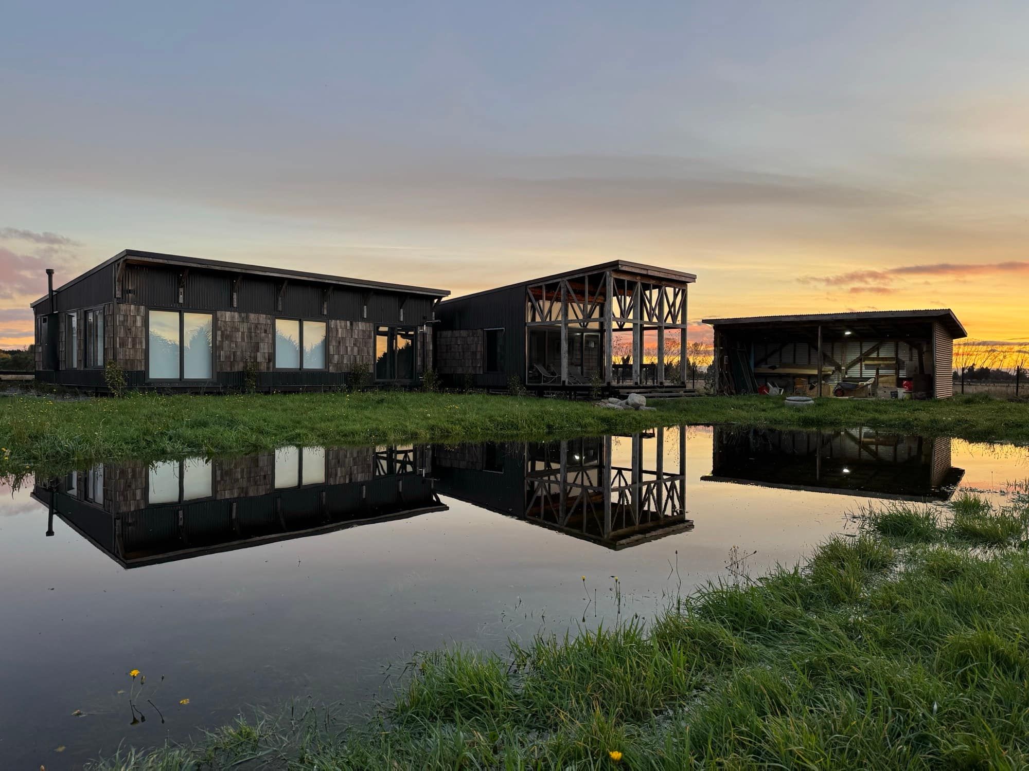 La casa al atardecer, reflejada en el agua de la pradera