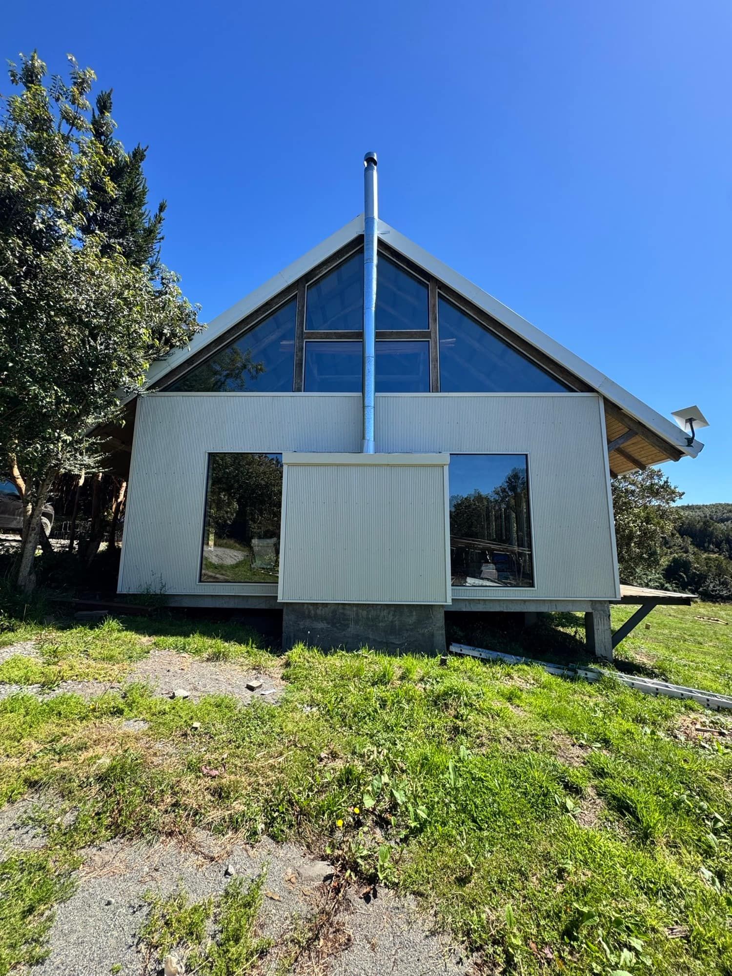 Fachada del galpón reconstruido: frontón claro y ventanal hacia la pradera
