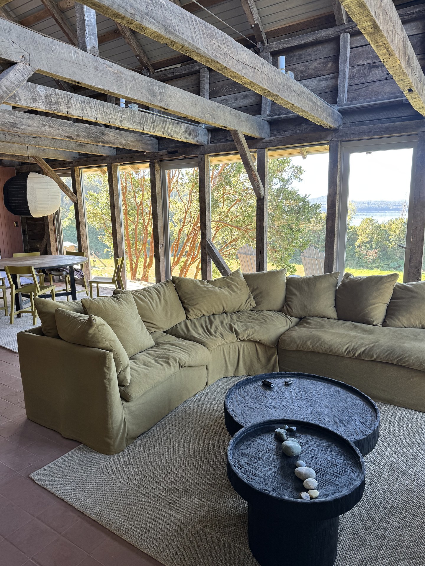 Interior principal — vigas centenarias de roble sobre piso terracota y sofa contemporáneo